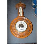 A late 19th Century aneroid barometer and thermometer in carved stained wood banjo pattern case