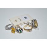 A quantity of costume rings, including: a fancy cut citrine ring set in white metal.