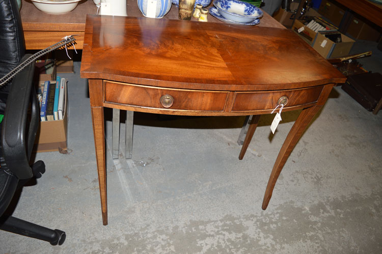 A mahogany bowfront reproduction side table with two frieze drawers.