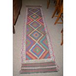 A Kilim runner with diamond-shaped medallions to field in bright colours.