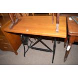 A black painted cast iron base of a sewing machine with later stained wood top.