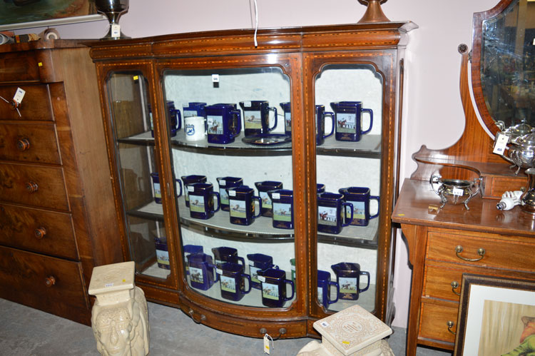 A bowfront inlaid stained wood display cabinet with glazed panels and underlying drawer.