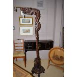 A carved dark stained wood lamp standard in the form of a dragon and clouds.