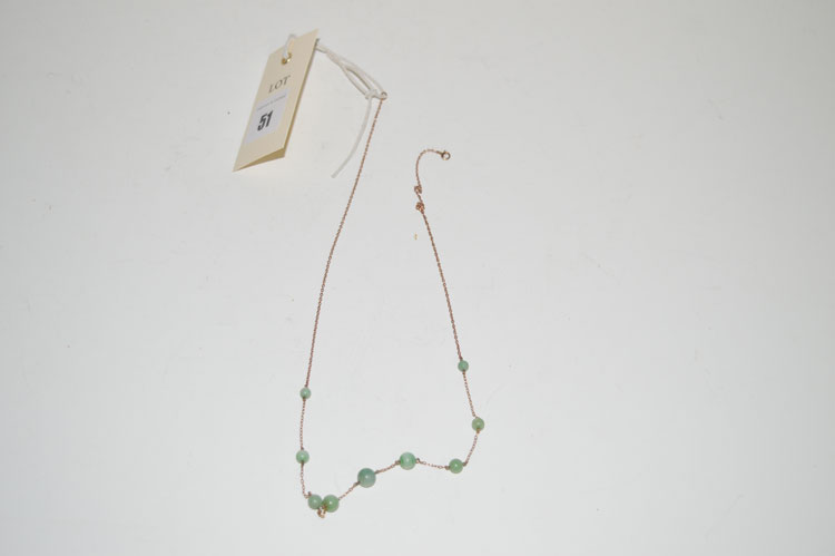 A yellow metal fine chain necklace set with jadeite graduated beads.