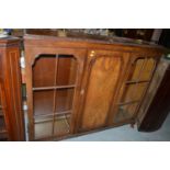 A first half 20th Century walnut cabinet, with two glazed doors flanking solid panel door.