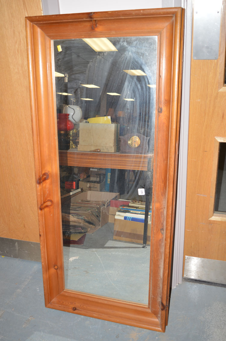 A stained pine framed rectangular wall mirror.