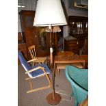 A stained wood and brass standard lamp with cream coloured shade.