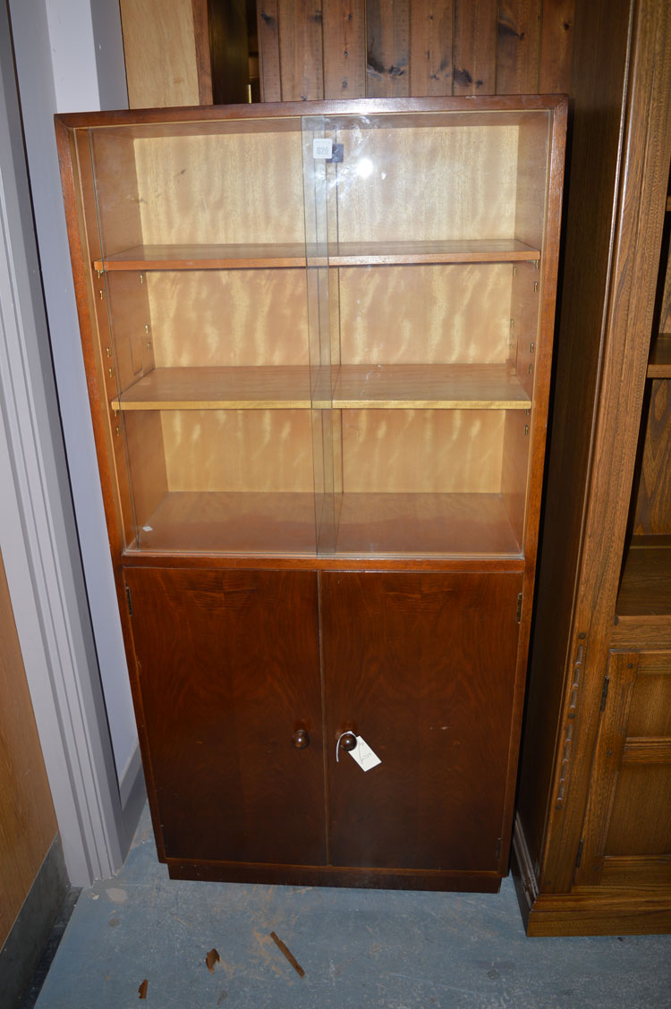 A stained wood bookcase, with glazed sliding doors enclosing shelves above a pair of solid doors.