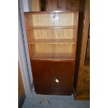 A stained wood bookcase, with glazed sliding doors enclosing shelves above a pair of solid doors.