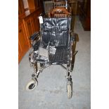 A folding wheelchair with padded back, arms and seat.