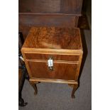 A figured walnut bedside cabinet, fitted a drawer above a compartment.