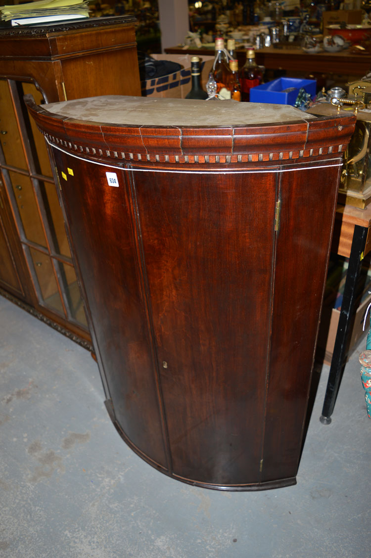 An early 19th Century mahogany bowfront hanging corner cabinet, with dentil flared cornice.