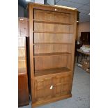 A dark stained wood open bookcase, with a pair of cupboard doors under.