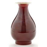 Red glaze pear shaped vase, with narrow neck rising to white glazed everted rim and interior,