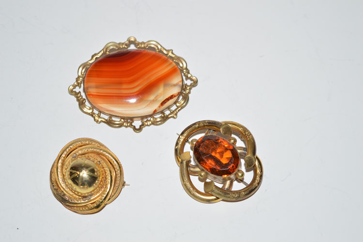 A 19th Century etruscan style roundel brooch; together with an agate set brooch; and another brooch.