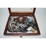 A quantity of costume jewellery in a glazed wooden case.