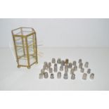 A large quantity of silver and metal thimbles in a glazed case.