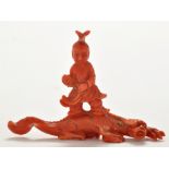 Chinese 'coral' carving of a boy standing on a lizard form beast, the boy with jovial expression,