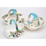 Two bone china hat-shaped baskets, one with a cat within the recess,