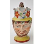 Painted pearlware character jug of Bacchus, bearded with fruiting vines upon his fringe,