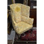 A 19th century wingback armchair raised on boldly hip carved front legs to paw feet