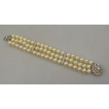 A three row uniform cultured pearl bracelet with two diamond-set white metal spacers on white metal