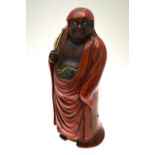 A Japanese glazed porcelain large figure of Daruma, scowling, in traditional red robe,