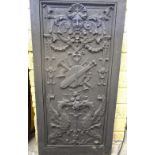 A cast iron panel, with relief mask, scroll and gryphon decoration, surrounding a musical trophy,