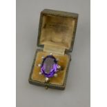 An oval facetted amethyst ring in 1960s style platinum setting, eight claws alternately set with