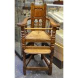 An antique oak child's high chair having a rope seat,