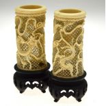 A pair of Chinese reticulated tusk vases, finely worked with dragons amongst clouds, on ebonised