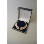 Asprey - a triple row uniform cultured pearl choker with diamond set stylised bow snap set overall