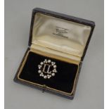 A pearl and diamond set circlet brooch having diamond set initials 'I L' in centre,