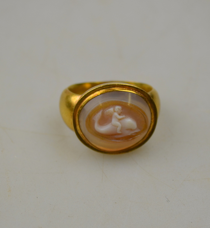 An ancient-style agate cameo ring of cherub riding a dolphin in hollow yellow gold setting Condition