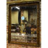 An antique moulded giltwood and plaster framed bevel edged mirror,