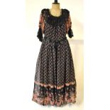 A 1970s Jean Varon black chiffon evening dress with pink/green floral sprays with black lace