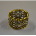 A Continental yellow and white metal pierced band, set with small diamonds, stamped 750, size P,