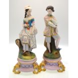 A matched pair of continental bisque figures of a lady and gentleman standing beside a tree trunk,