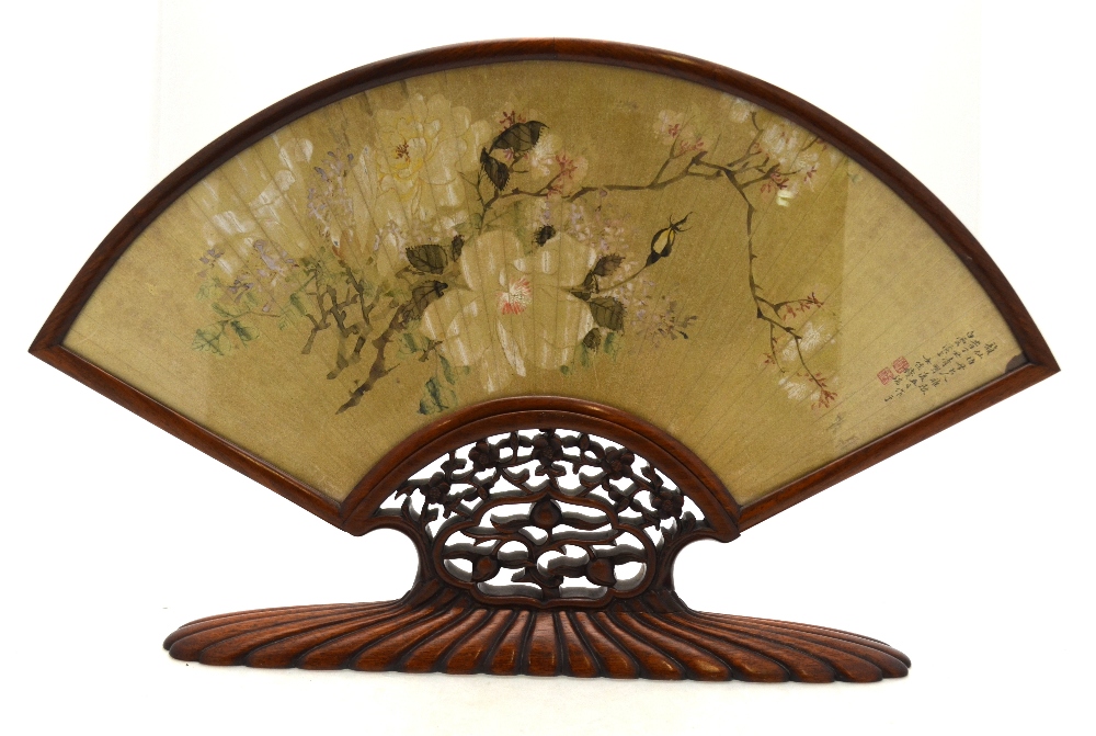 A Chinese gilded paper fan painted with tree branches in blossom,