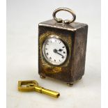 A miniature silver desk-clock of rectangular form, with loop handle and bun feet,