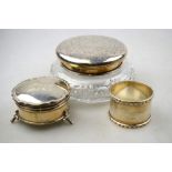 A circular silver ring-box with blue silk and velvet lining and gilt interior, on scroll feet,