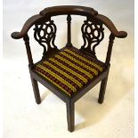 A George III mahogany corner elbow chair with fret cut splats over a cushion seat,