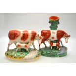 A Victorian Staffordshire model of a cow and calf raised on a naturalistic oval base,