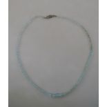 A single row of faceted graduated aquamarine beads on metal snap stamped silver