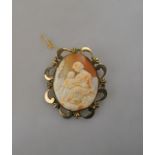 A large oval shell cameo brooch featuring mother and child, in gilt metal scroll style mount,