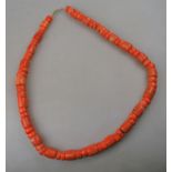 A single row of large coral beads of mixed cylindrical shapes