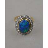 An oval black opal ring having brilliant cut diamonds around, in open basket style setting,