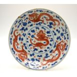 A Chinese circular dish decorated with a border of dragons chasing flaming pearls of wisdom,