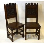 A pair of carved oak panelled 17th century style chairs with boarded seats,