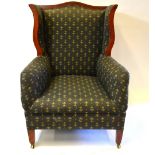 An Art Nouveau period walnut framed fleur de lys pattern upholstered shaped wing back armchair